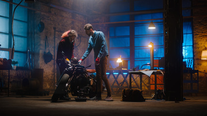 Fototapeta na wymiar Two Young Professionals are Discussing The Work Done on a Custom Bobber Motorcycle. Hipster Man Explaining the Job to a Talented Female Mechanic. Authentic Workshop Garage.
