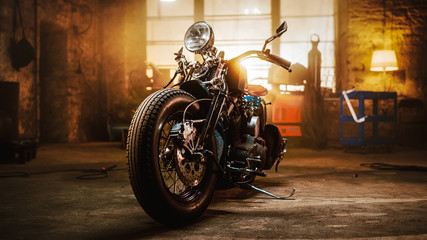 Kundenspezifisches Bobber-Motorrad, das in einer authentischen Kreativwerkstatt steht. Motorrad im Vintage-Stil unter warmem Lampenlicht in einer Garage.