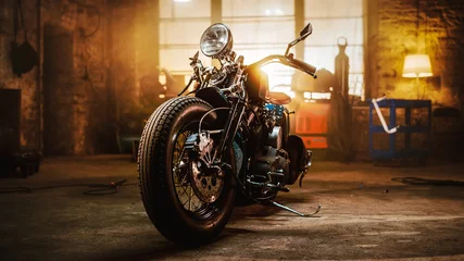 Foto auf Acrylglas Motorrad Kundenspezifisches Bobber-Motorrad, das in einer authentischen Kreativwerkstatt steht. Motorrad im Vintage-Stil unter warmem Lampenlicht in einer Garage.