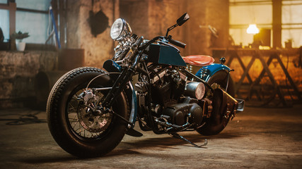 Kundenspezifisches Bobber-Motorrad, das in einer authentischen Kreativwerkstatt steht. Motorrad im Vintage-Stil unter warmem Lampenlicht in einer Garage.