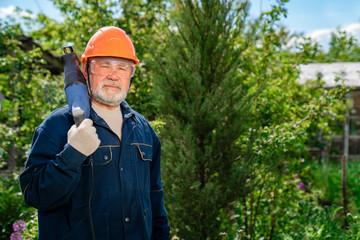 elderly man with beard in hardhat and glasses with reciprocating saber saw. 