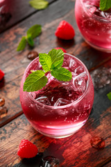 Refreshing raspberry cocktail with ice and mint on wooden table