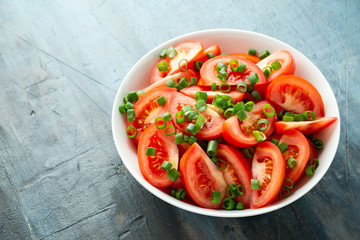 Tomato salad with spring onion and herbs in white bowl. Healthy summer food