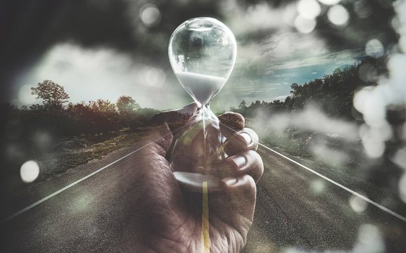 Double exposure open road and hand holding hourglass. life time passing concept.