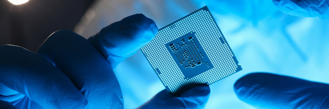 Hands in gloves hold chip testing microelectronics