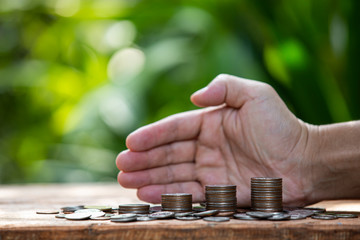 Coins in glass jar set on wooden plates, put in a green background