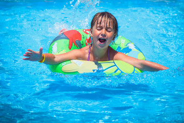 Beautiful child girl in swimming pool relax swim on inflatable ring. Summer holiday, vacation and happy childhood.
