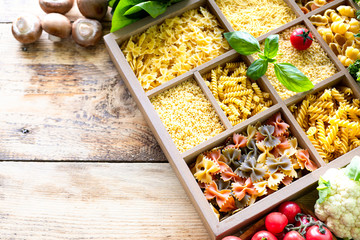 Different types of italian uncooked pasta in wooden box, whole wheat pasta, pasta, spaghetti, noodles, tagliatelle. Top view