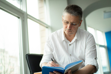 Fototapeta premium A man in a white shirt makes a note in a notebook.
