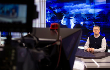 A male News anchor in a broadcast Studio reads text on a teleprompter. Camera in the TV Studio.