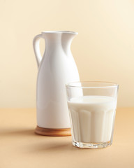  Glass of milk and milkman on a brown background. Minimalism. The concept of farm dairy products, milk day. Copy space.