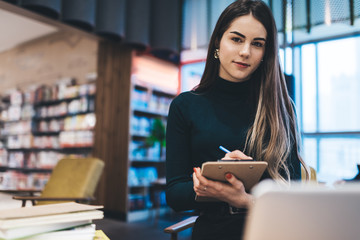 Smart woman with clipboard in library