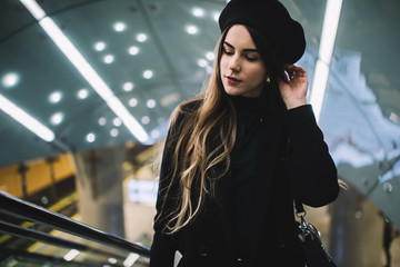 Young woman in trendy stylish outfit standing on stairs in subway