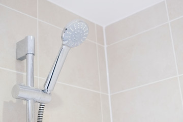 Chrome modern shower head and neutral tiles in bathroom ensuite