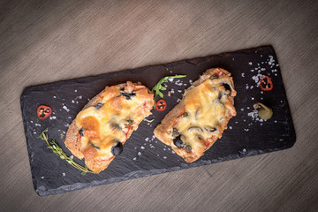 Two brutal sketches with cheese, olives, mushrooms on stone plates. restaurant giving. for the menu of cafe. wooden table. salt, pepper