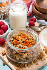 homemade granola with dried apricots and nuts in a jar, vertical top view
