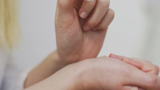 Pretty young woman applying roller perfume on her hands