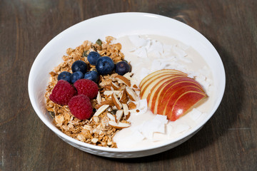 oat granola with apples and berries on wooden background