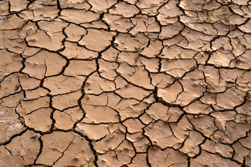 Cracked soil landscape texture on ground earth with natural light sunset of the sun with dramatic yellow and orange sky. Image depth of field.