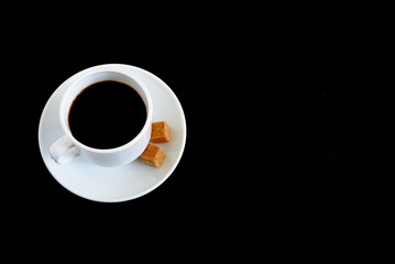 Coffee in a white mug, and two lumps of sugar. Above, on a black background. Suitable for background. Mockup