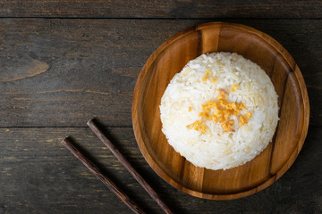 Rice with fried garlic in wooden dish on wooden table.