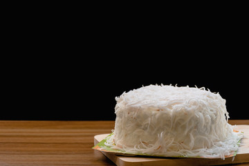 White coconut cake on wooden table with black background and nature light, Selective focus.