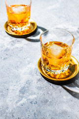 Whiskey tumblers with ice blocks on marble surface