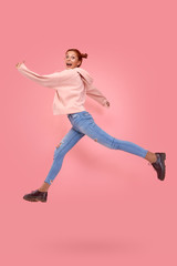 Fototapeta na wymiar Full length side profile of emotional cheerful beautiful energetic caucasian red-haired female hipster jump on in the air, hurry shopping black Friday, low prices isolated over pink studio background