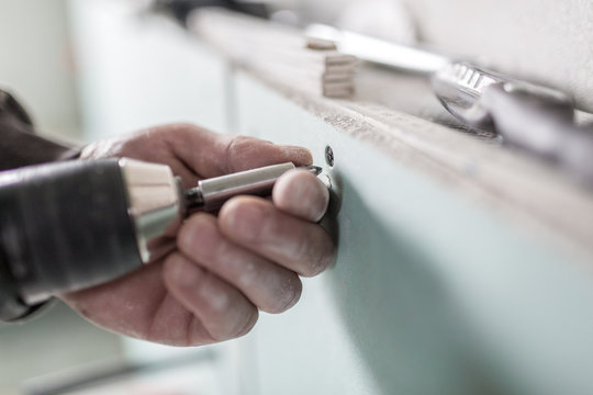 Ein Handwerker schraubt eine Schraube in eine Gipsplatte und montiert sie an der Wand