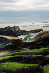 Long exposure photography of sea waves and mist on the rocks of the shore of Porto Novo
