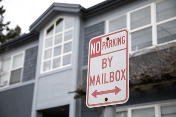 "No Parking By Mailbox" sign with apartment in background