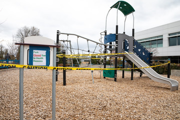 Playground with caution tape and "Park Closed Due to Health Reasons" sign