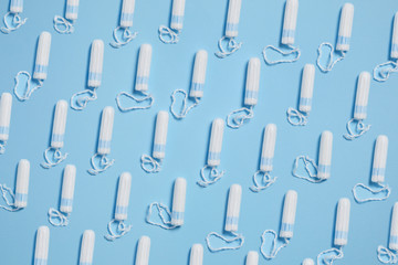 Pattern with white sanitary hygienic cotton tampons on blue background. Feminine hygiene products. Top view