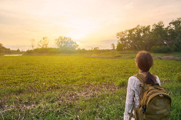  woman is carrying a bag and looking at nature with the sunset