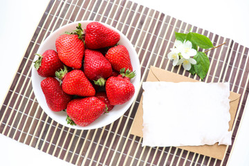 ripe strawberries on a white plate and jasmine flowers. still life