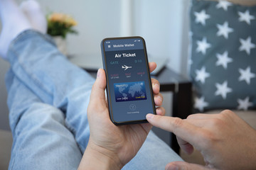 male hands holds phone with airplane ticket application airlines screen