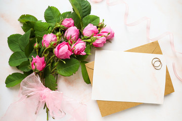 mock wedding card. bouquet of pink roses and a wedding ring on a white background. congratulation. wedding invitation