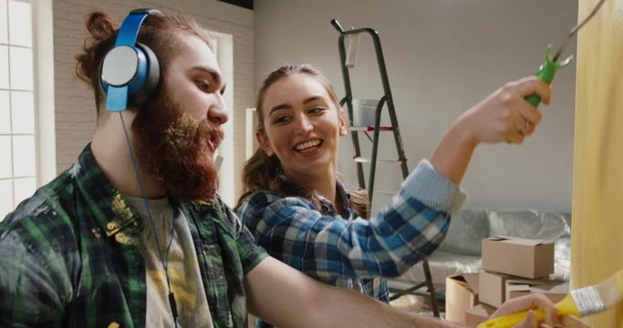 Newlywed caucasian couple is renovating their new home, painting the walls and positively smiling - new life, young family, mortgage concept 4k footage