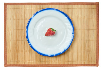 lonely strawberry on a white plate with a blue rim on a cane place mat