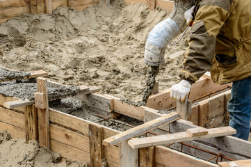 Pouring cement into a wooden formwork for the Foundation of a building that is being built.