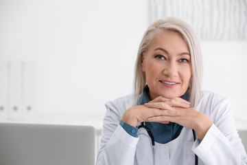 Portrait of mature female doctor in white coat at workplace