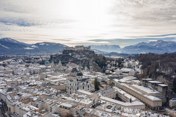 Aerial drone shot view of snowy salzburg city center with view of Cathdrals and fortress in winter