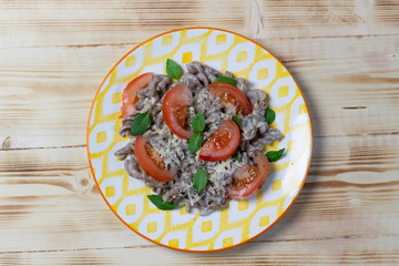 brown rye pasta with white sauce, basil leaves, tomato, cheese, pepper in  plate on wooden background