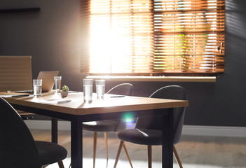 Stylish office interior with wooden table in morning