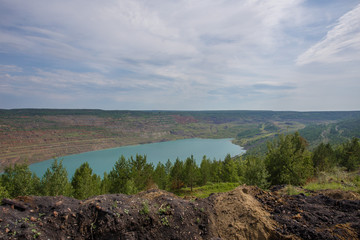 Abandoned coal ore quarry open pit flooded with blue water