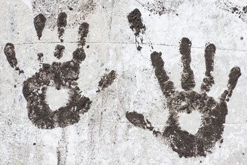 Black handprints on an old white wall. Silhouettes of the heart on the palms.