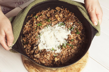 Cooked buckwheat with dried mushrooms and Parmesan in a cast iron pot. Vegetarian food. Russian,...