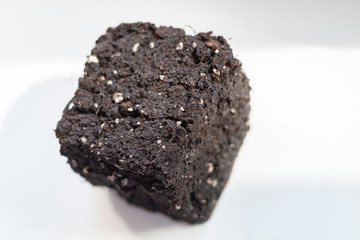 A separate object in the form of a cube from the soil on a light background in soft focus