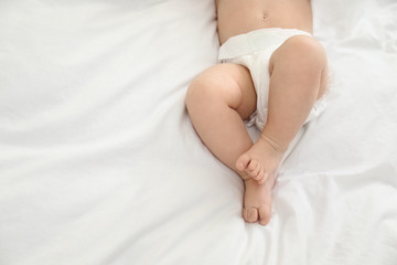 Cute little baby in diaper on bed, top view. Space for text