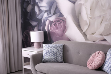 Modern sofa near wall with floral wallpaper. Stylish living room interior